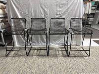 Front view of four black wire metal barstools lined up