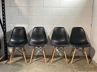 Four chairs in a row, front view against a white block wall