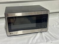 Front angle view of a stainless steel LG microwave oven showing door, control panel, and button.