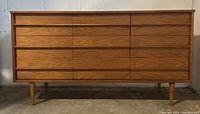 Front view showing entire dresser with nine drawers and tapered legs