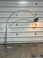 Full view of chrome arc floor lamp with base, stem, curved arm, and shade