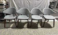 Set of four grey fabric dining chairs with wooden legs, showing a Mid-Century Modern style. All chairs have seats detached from the base requiring repair.