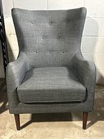 Front view showing button tufted back, seat cushion and tapered legs