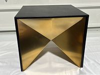 Front angled view showing black square top and metallic gold geometric cubist inset base forming triangular shapes