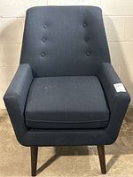 Front view of a dark blue navy lounge chair by Structube with a buttoned backrest, padded seat cushion, and four angled wooden legs.