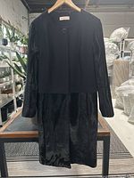 Full view of the jacket and skirt set hanging on a hanger before any display or arrangement.