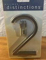 Photo of new Hillman Distinctions house number 2 in original packaging, including installation screws.