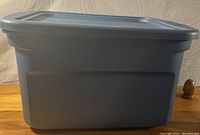 Side profile photo of blue plastic storage tub with lid on, showing tub shape and handles.