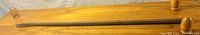 Single long metal crow bar with wooden handle and knob.