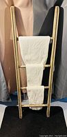 Full view of wooden ladder towel holder with three rungs, showing its shape and condition.