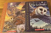 Photo showing two paperback books: 'The Siege' and 'The Journey' from the Guardians of Ga'Hoole series, by Kathryn Lasky, published by Scholastic.