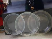 Photo of three clear glass Pyrex pie plates stacked on a black surface
