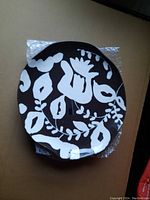 Top view of one decorative dinner plate showing brown background with cream floral and leaf design.
