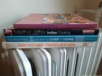 Side view showing titles and authors of four cookbooks stacked together.