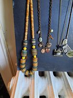 Photo showing various necklaces arranged on a dark background, including beaded and charm styles