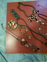 Photo showing the assortment of bracelets and necklaces laid out on a reddish surface.
