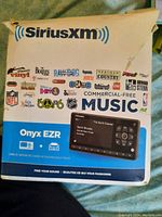 Box packaging displaying SiriusXM Onyx EZR system branding, logos of music and radio channels, and photo of the radio unit screen.