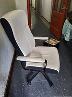 Side view of white and black office chair showing cushioned seat, backrest, armrests, and black base.