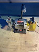 Front view of the Craftsman bench grinder showing both grinding wheels, motor housing and flexible work light.