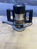 Front view of Black & Decker plunge cut router with handles and power cord on wooden surface.