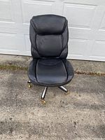 Front view of black leather desk chair showing padded seat, backrest, and metal base with casters.