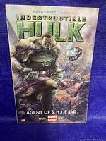 Front cover of Indestructible Hulk graphic novel titled 'Agent of S.H.I.E.L.D.' showing the Hulk in an action pose with a weapon.