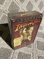 Shrink-wrapped box set of The Adventures of Indiana Jones widescreen 4-disc DVD collection showing front cover art with Indiana Jones in his signature hat and whip.