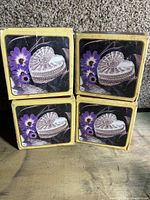 Four yellow boxes each containing a heart-shaped crystal dish. The boxes show an image of the dish with purple flowers on the cover.