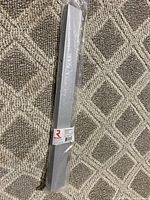 Silver-colored Richelieu pull handle wrapped in plastic on carpeted floor.