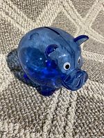 Front view showing the piggy bank's facial features including eyes, ears, snout, and the coin slot on top.