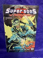 Front cover of the Super Sons of Tomorrow graphic novel showing colorful superhero artwork with Batman and two young characters.