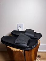 Side view of black Bench slides showing embossed logo on strap and cushioned sole