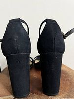 Back view of the black suede ankle strap heels showing the block heels and suede texture.