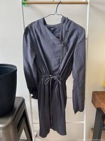 Full view of the grey lightweight jacket hanging on a hanger. The jacket has long sleeves, zipper closure, and a hood.