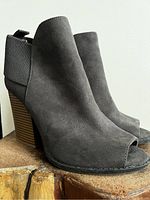 Side angle shot of a grey suede peep toe bootie showing the front, side and heel.