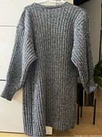 Full back view of the knitted cardigan showing textured ribbed pattern, long puff sleeves, fitted cuffs, and side slits.