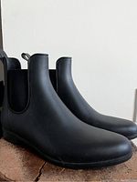 Side and front profile of Cougar black rubber ankle-high rain boot showing smooth finish and shape