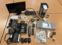 Photo showing assortment of electronics on table including monitor, keyboard, Keurig, CD player, phones, cords, and mice.