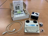 Photo showing Ultratec Superprint 4425 device, manual, power cord, Sony camera box, and headset bags laid out on table.