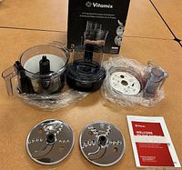 Full set of Vitamix 12-cup food processor attachment parts including box, bowl, feed chute, lid, discs and manual.