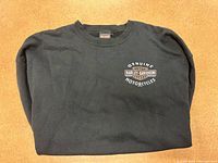 Front left chest logo showing 'Genuine Harley-Davidson Motorcycles' on black crew neck sweatshirt.