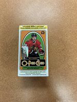 O-Pee-Chee 2013-14 hockey card box featuring a player in a red Chicago Blackhawks jersey and text about exclusive insert cards inside.