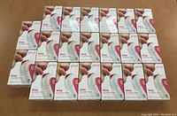 Twenty boxed PMD Kiss Lip Plumping Systems arranged in a grid on a table