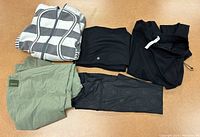Overview of lot with striped zip-up sweater and four pairs of pants in different colors and styles