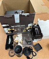 Photo showing the open and partially assembled box containing the Nespresso Vertuo machine, Aeroccino 3 frother box, manuals, and accessories.