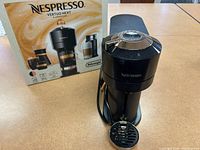 Nespresso Vertuo Next coffee machine with Aeroccino3 milk frother and original box, showing front side of the coffee machine and frother with drip tray.