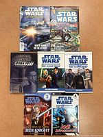 Photo showing 7 Star Wars comics and readers arranged on surface with visible covers featuring characters like Darth Vader, Boba Fett, Obi-Wan Kenobi and Clone Wars themes