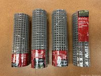 Four rolls of galvanized welded hardware mesh wrapped and labeled including brand and specifications.