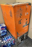 Box of Worx Nitro cordless lawn mower with visible wear and some tape on packaging.