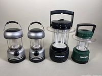 Four LED utility lanterns displayed in a row: two silver North 49 lanterns on left, black Rayovac lantern second from right, green Rayovac lantern on right
